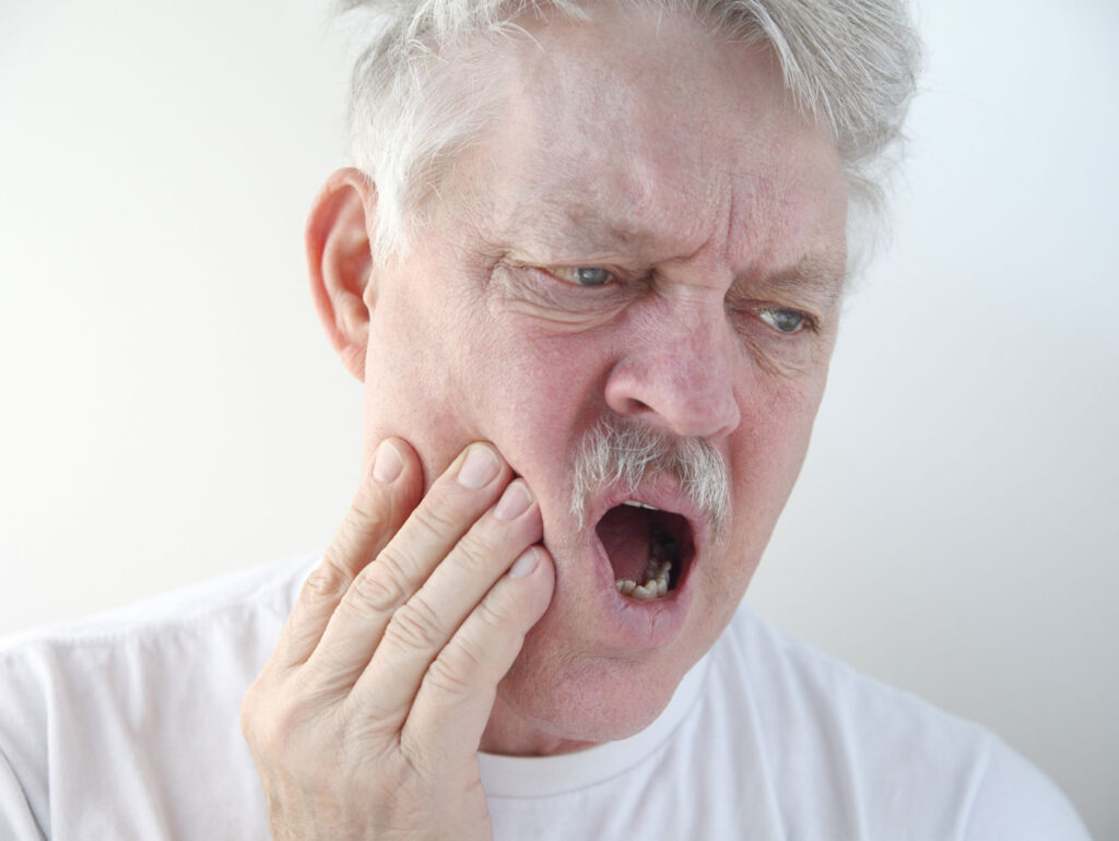 man holding jaw from TMJ jaw pain in winter