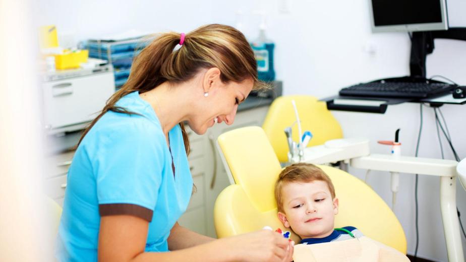 gentle pediatric dentist explaining checkup steps to child