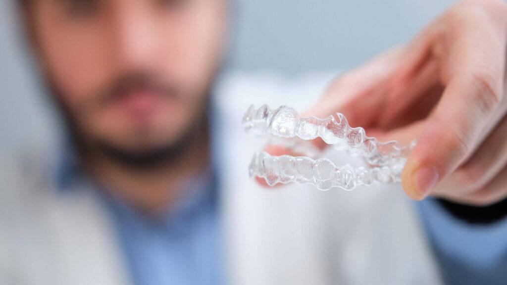 Dentist placing tooth-colored attachments used with clear aligners for precise movement
